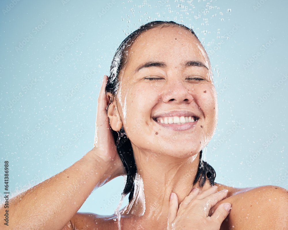 Skincare, shower and happy woman washing hair in studio isolated on a blue background. Water splash,