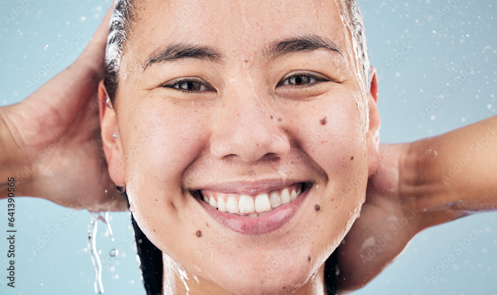 Face, shower and happy woman cleaning hair in studio isolated on blue background. Water splash, hygi