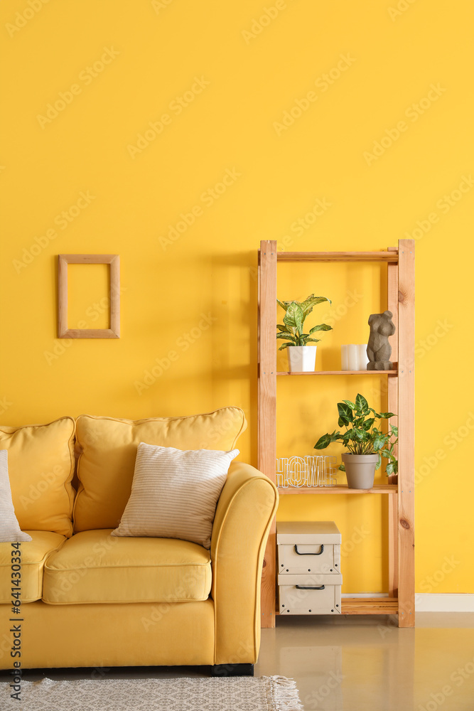 Interior of living room with yellow sofa and shelving unit