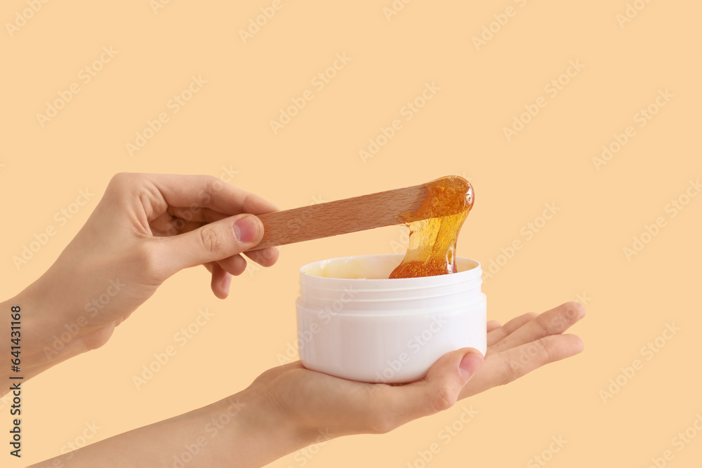 Female hands holding sugaring paste on beige background