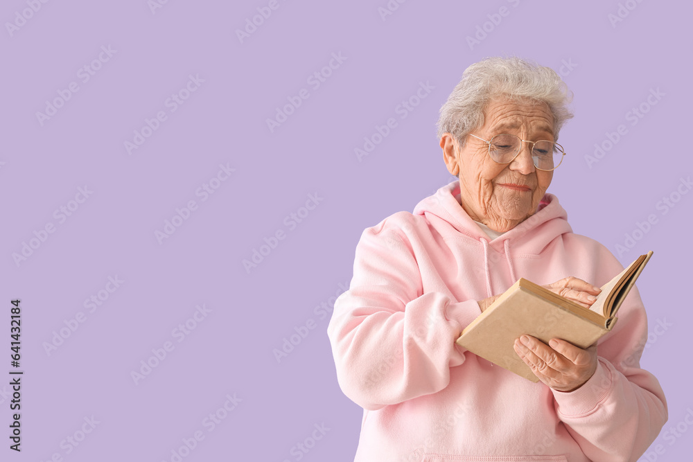 Senior woman reading book on lilac background