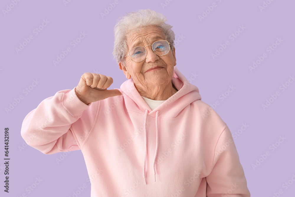 Senior woman pointing at herself on lilac background