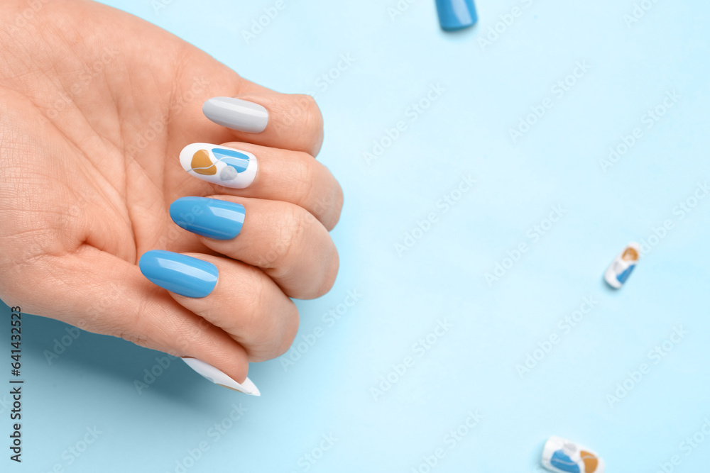 Woman with press-on nails on blue background, closeup