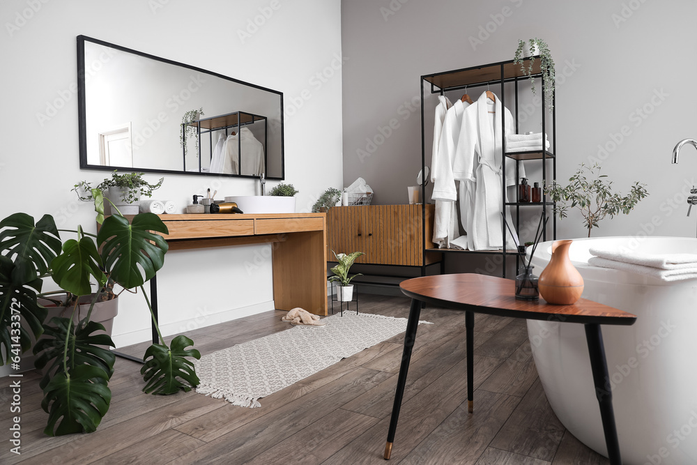 Interior of light bathroom with shelving unit, bathrobes and sink