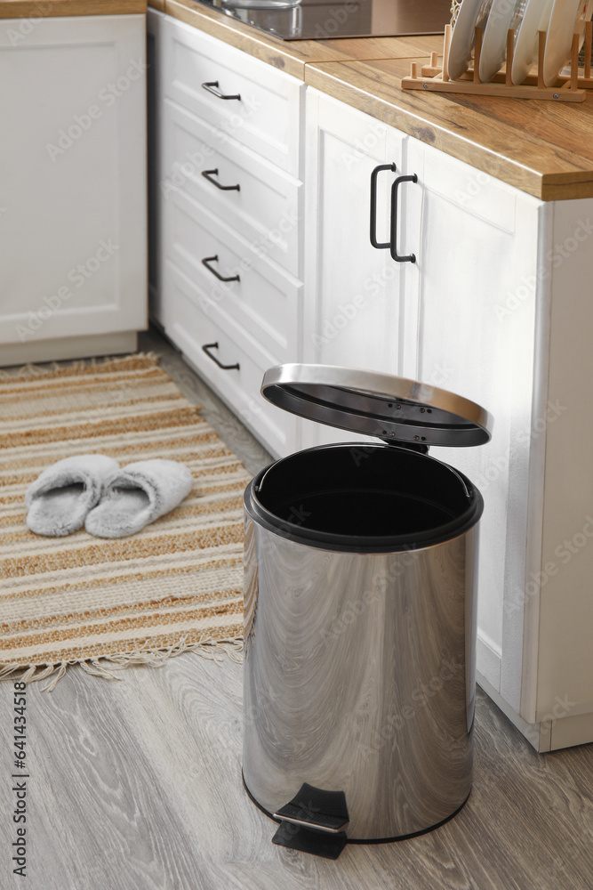 Opened metallic trash bin on floor in modern kitchen