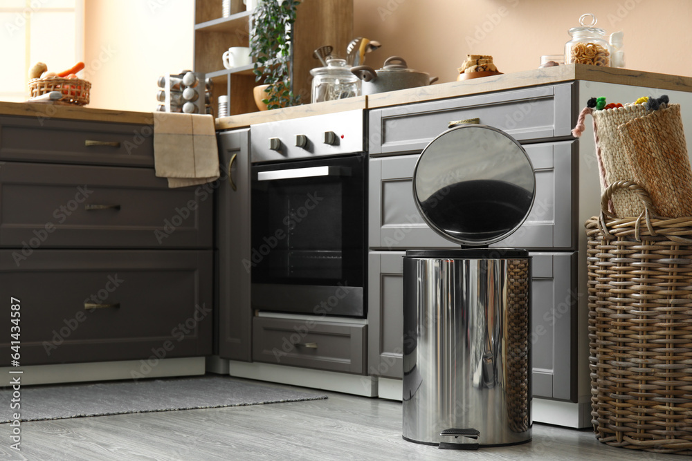 Opened metallic trash bin on floor in modern kitchen