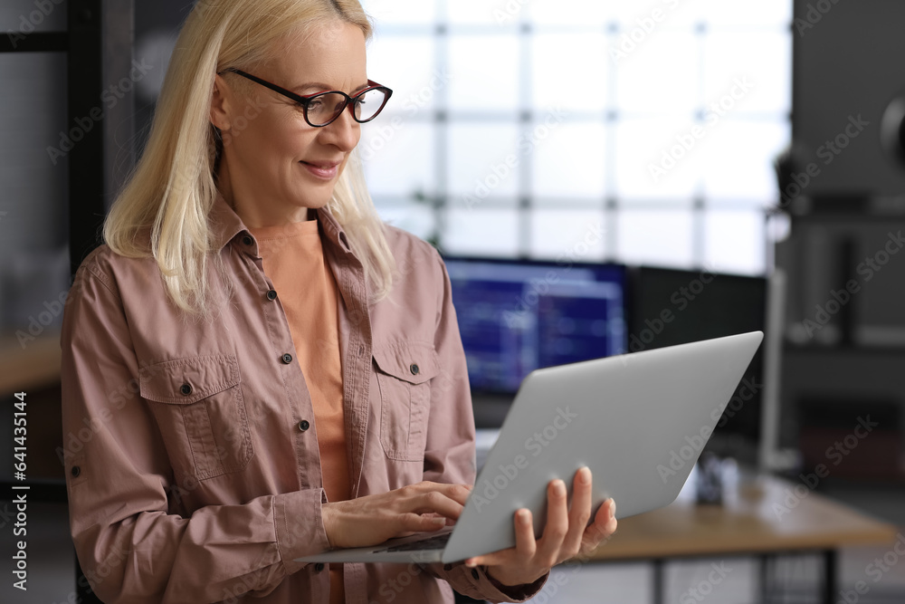 Mature female programmer working with laptop in office