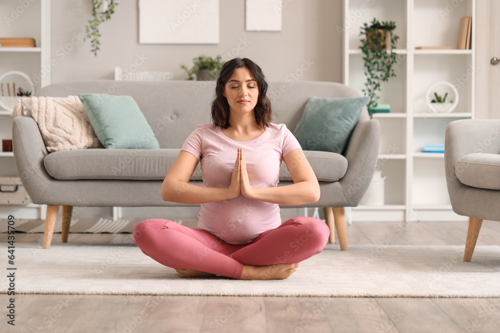 Sporty pregnant woman meditating at home