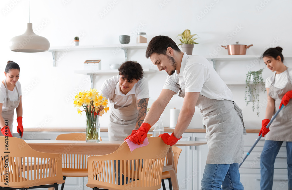 Young janitors cleaning in kitchen