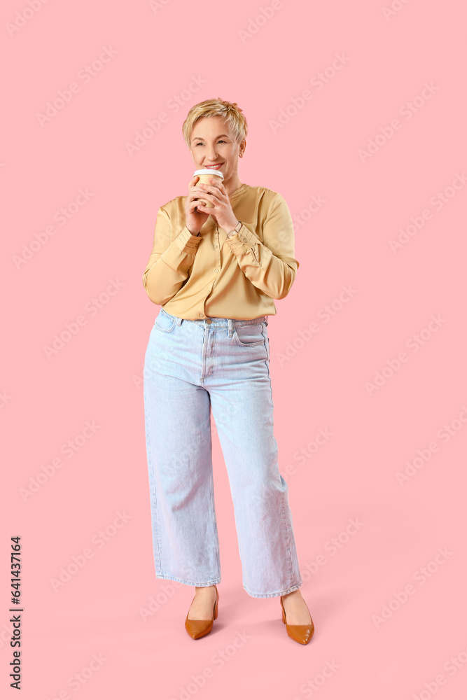 Dreaming mature woman with cup of coffee on pink background