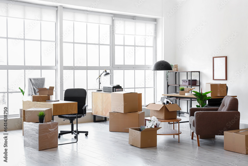 Interior of light office with cardboard boxes on moving day