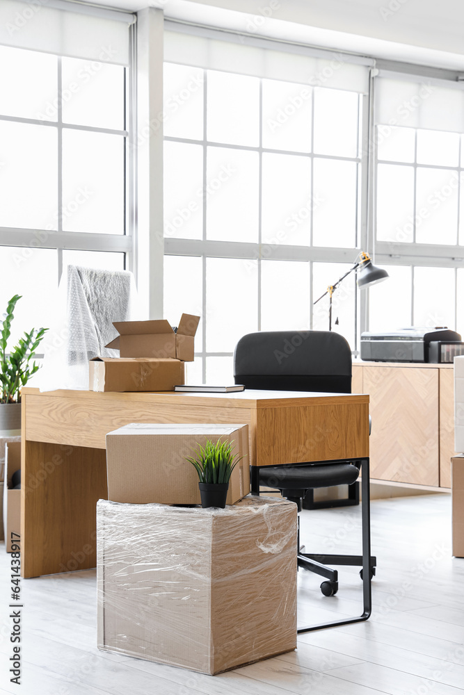 Interior of light office with cardboard boxes on moving day