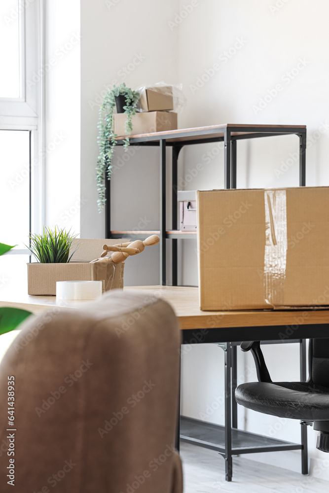 Interior of light office with cardboard boxes on moving day