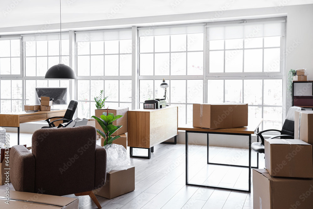 Interior of light office with cardboard boxes on moving day