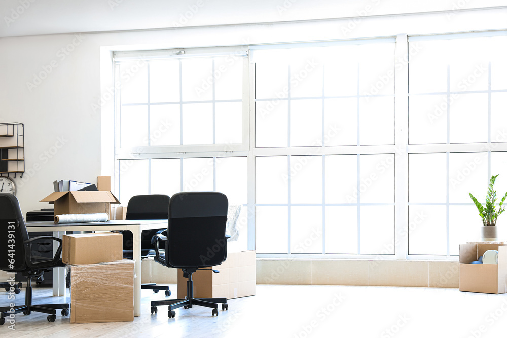 Interior of light office with cardboard boxes on moving day