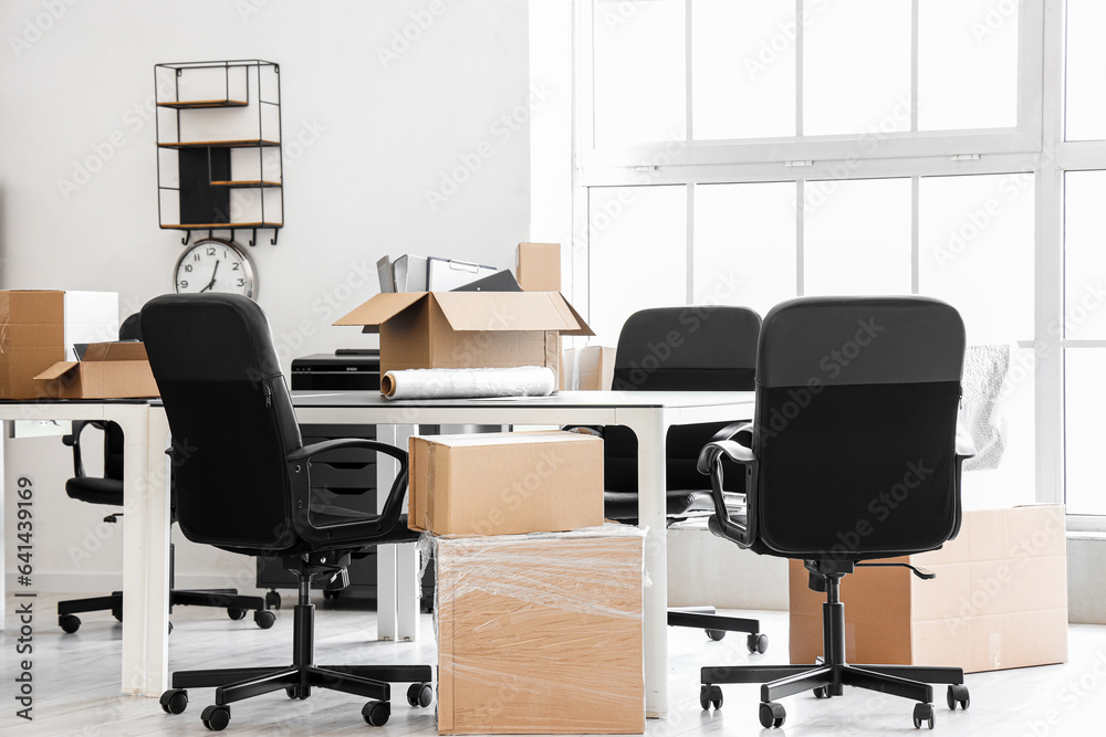 Interior of light office with cardboard boxes on moving day