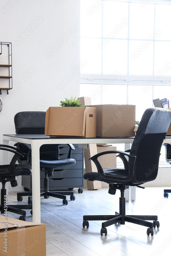 Interior of light office with cardboard boxes on moving day