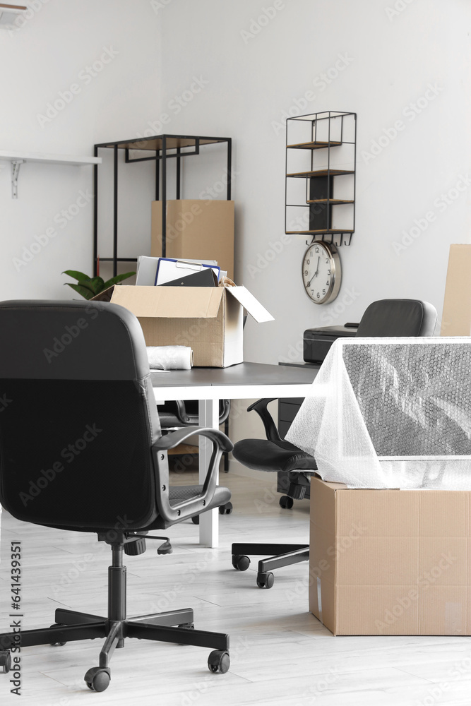 Interior of light office with cardboard boxes on moving day