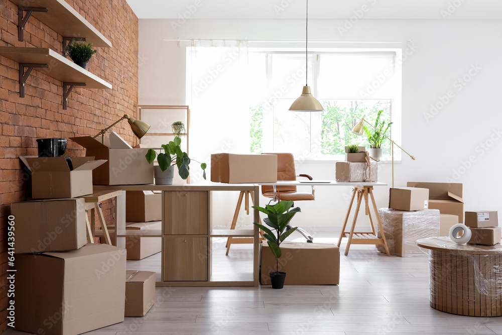 Interior of stylish office with cardboard boxes on moving day