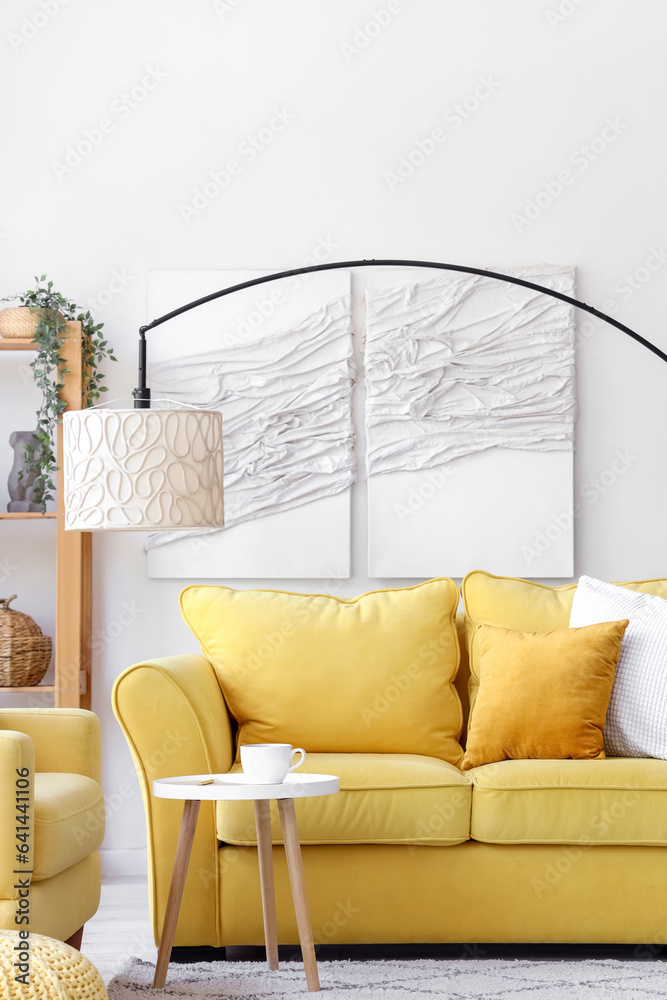 Interior of light living room with yellow sofa and armchair