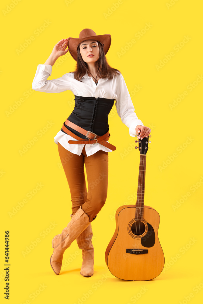 Beautiful cowgirl with guitar on yellow background