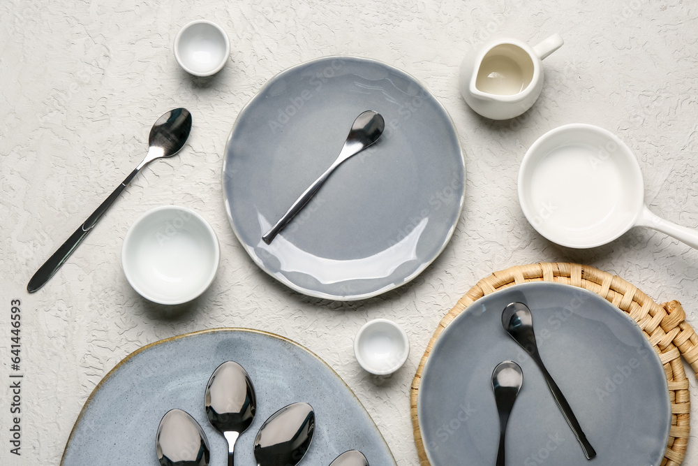 Table setting with clean plates and spoons on grey background