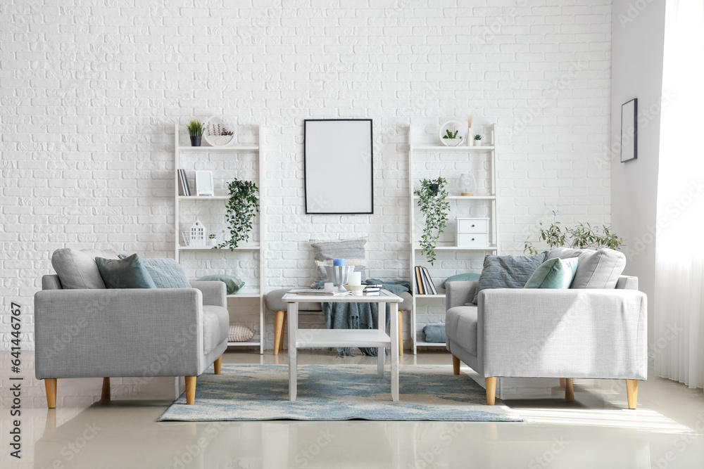 Interior of light living room with cozy grey sofas and coffee table