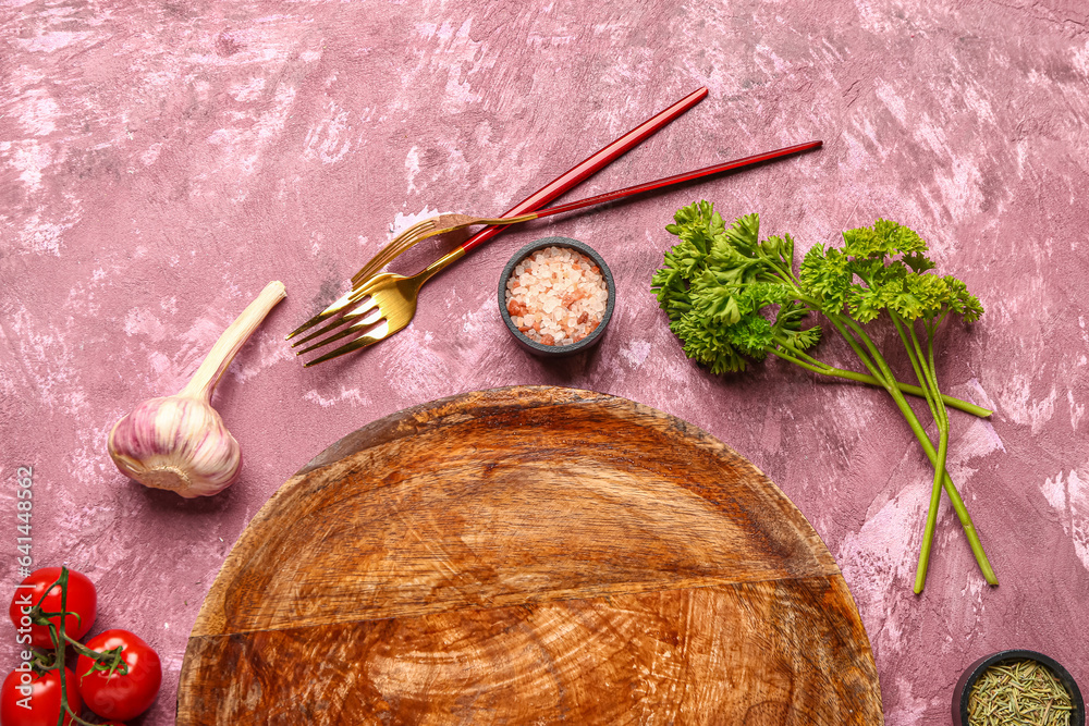 Composition with wooden kitchen board and different spices on color background