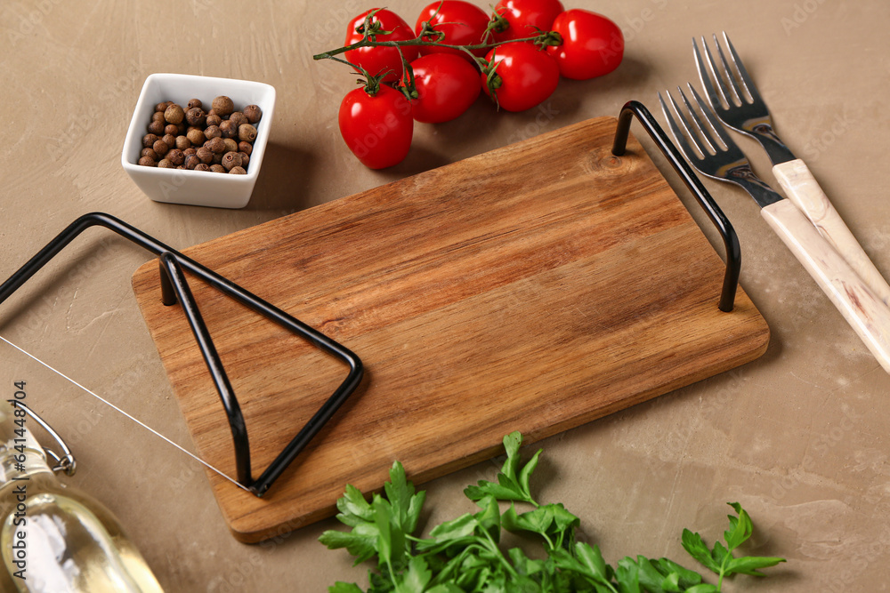 Wooden kitchen board, spices, tomatoes and parsley on color background