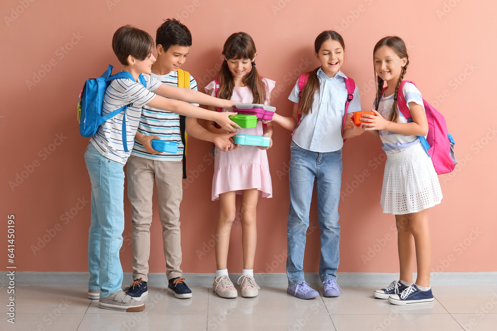 Little pupils with lunchboxes and backpacks near pink wall