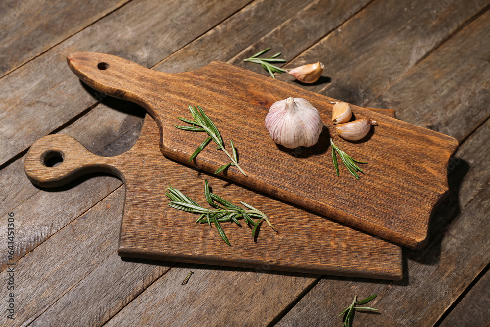 New cutting boards with garlic and rosemary on wooden background