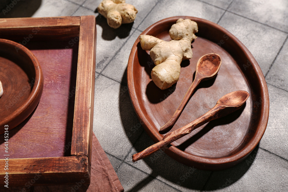 Wooden plate and tray with garlic on grey tile background