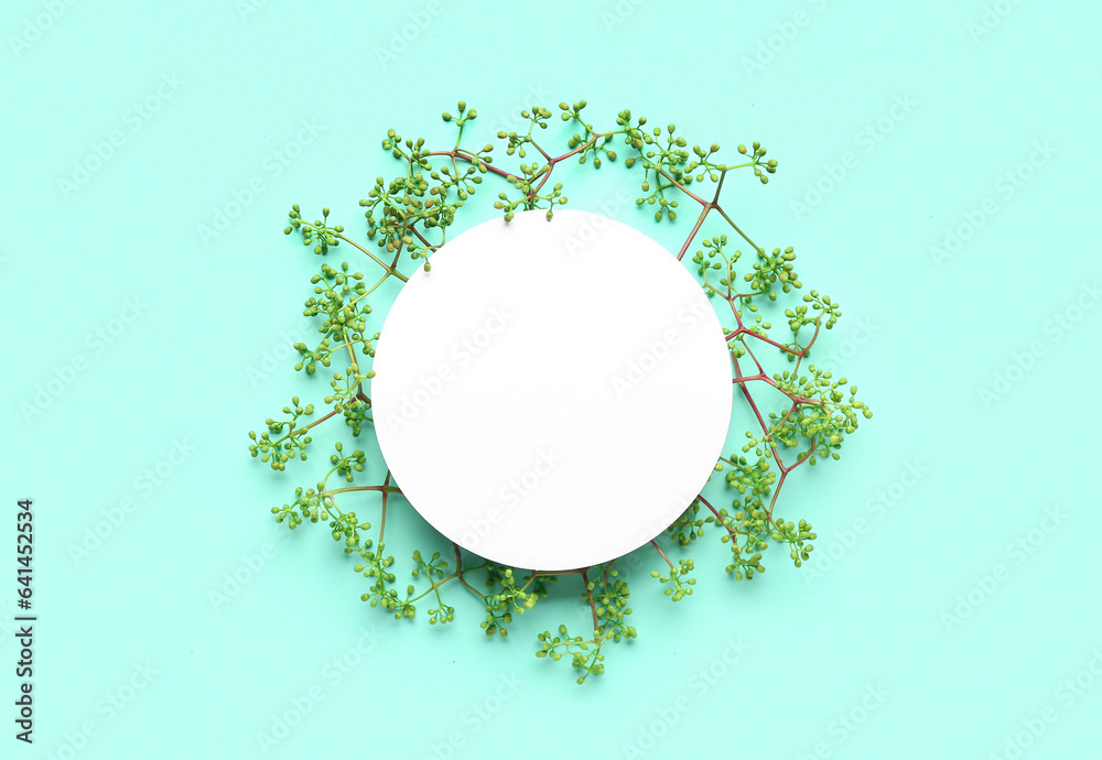 Green twigs with round blank card on turquoise background