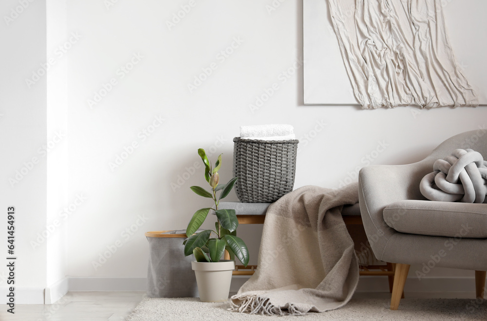 Interior of light living room with armchair and wicker basket