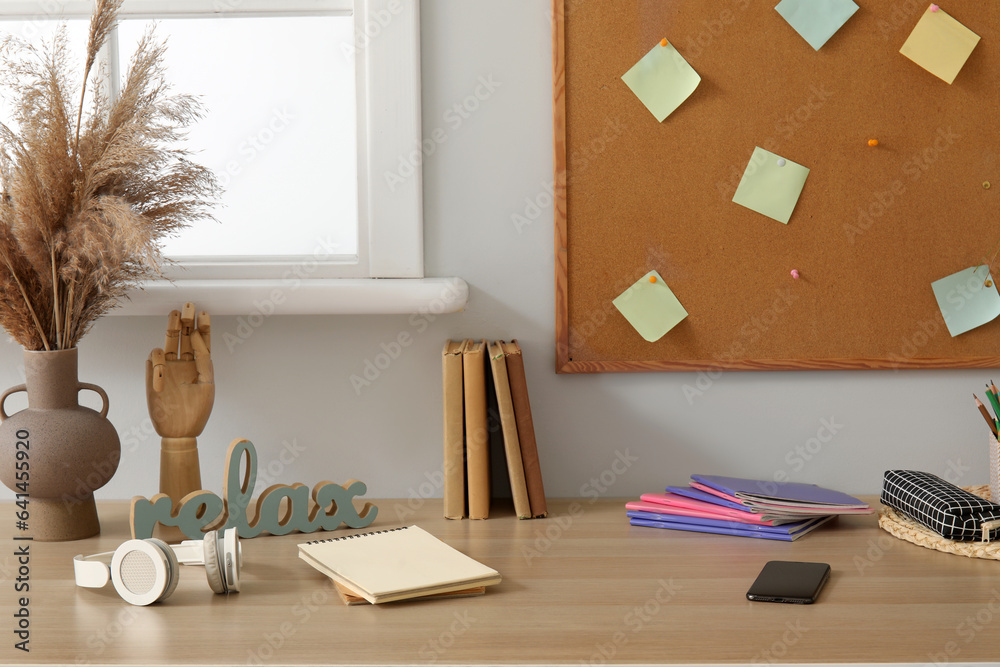 Modern school desk with stationery in room near white wall