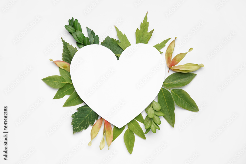 Blank heart shaped card and green leaves on white background