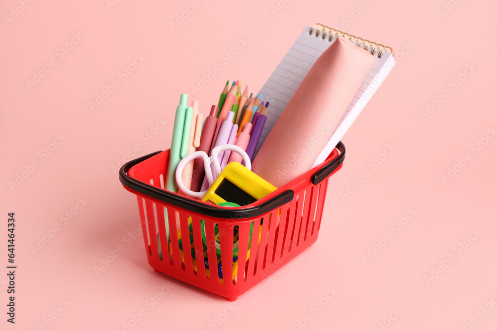 Basket with different stationery on pink background