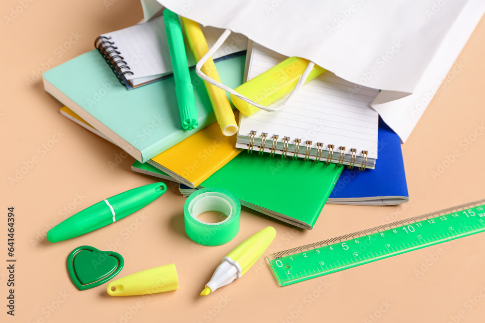 Paper bag with stationery on color background, closeup