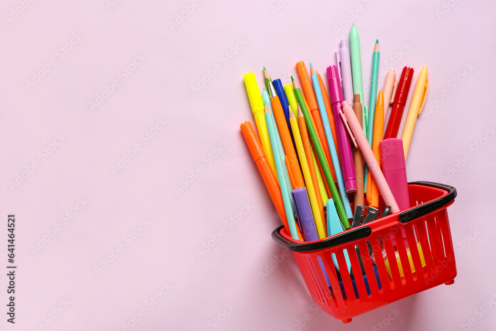 Shopping basket with different stationery on pink background