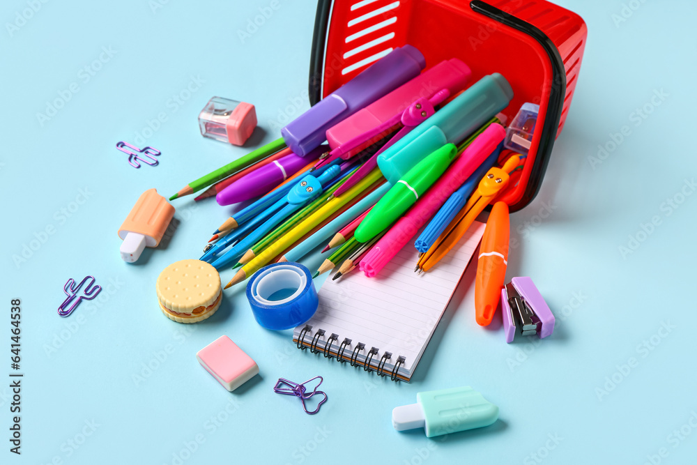 Composition with shopping basket and stationery on color background