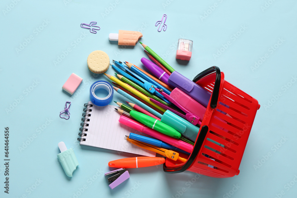 Composition with shopping basket and stationery on color background