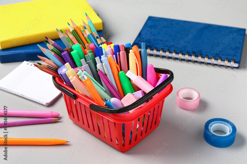 Shopping basket full of different stationery on grey background