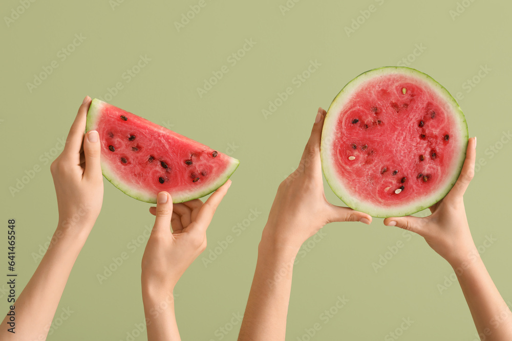 Female hands with half and slice of ripe watermelon on green background