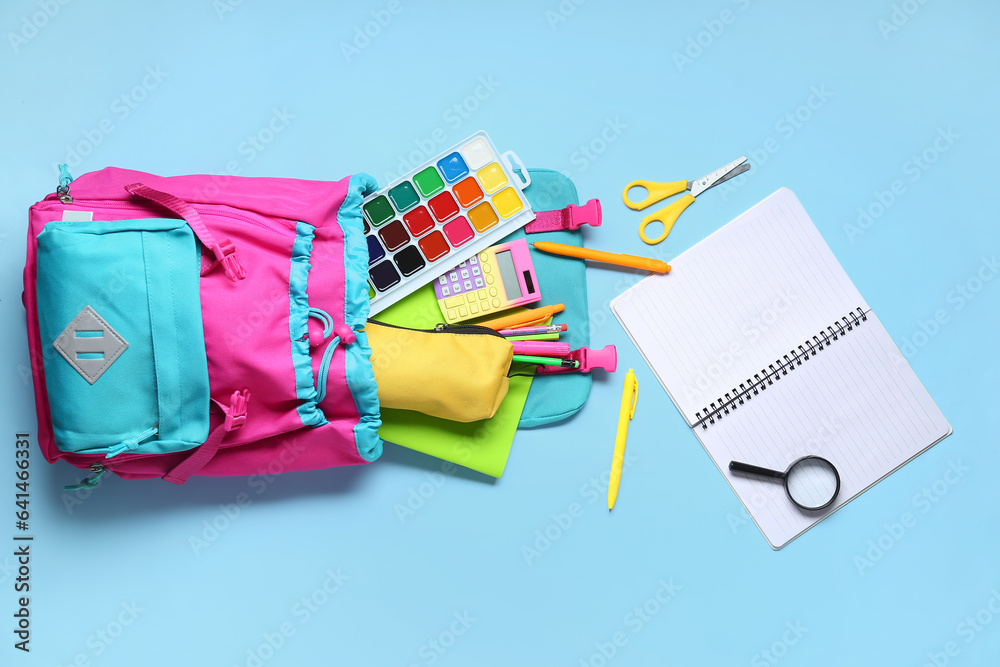 Stylish school backpack with different stationery on blue background