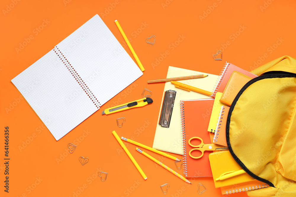 Stylish school backpack and different stationery on orange background