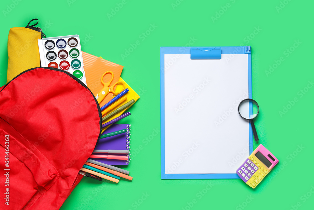 Stylish school backpack and different stationery on green background