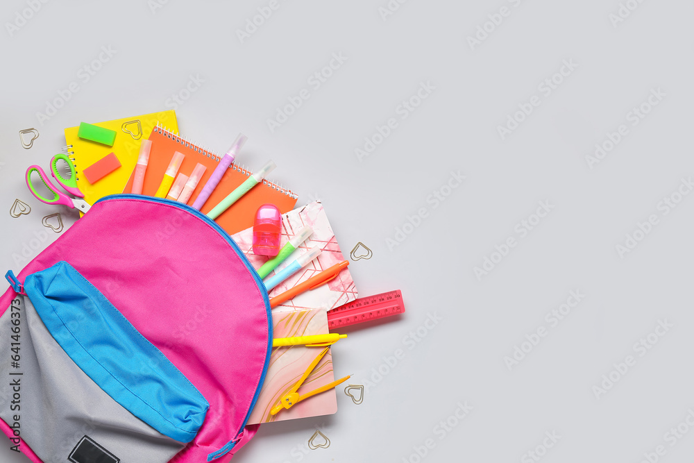 Stylish school backpack with different stationery on grey background