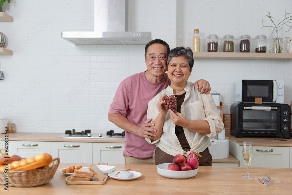 Asian senior eating fruits together in her modern kitchen