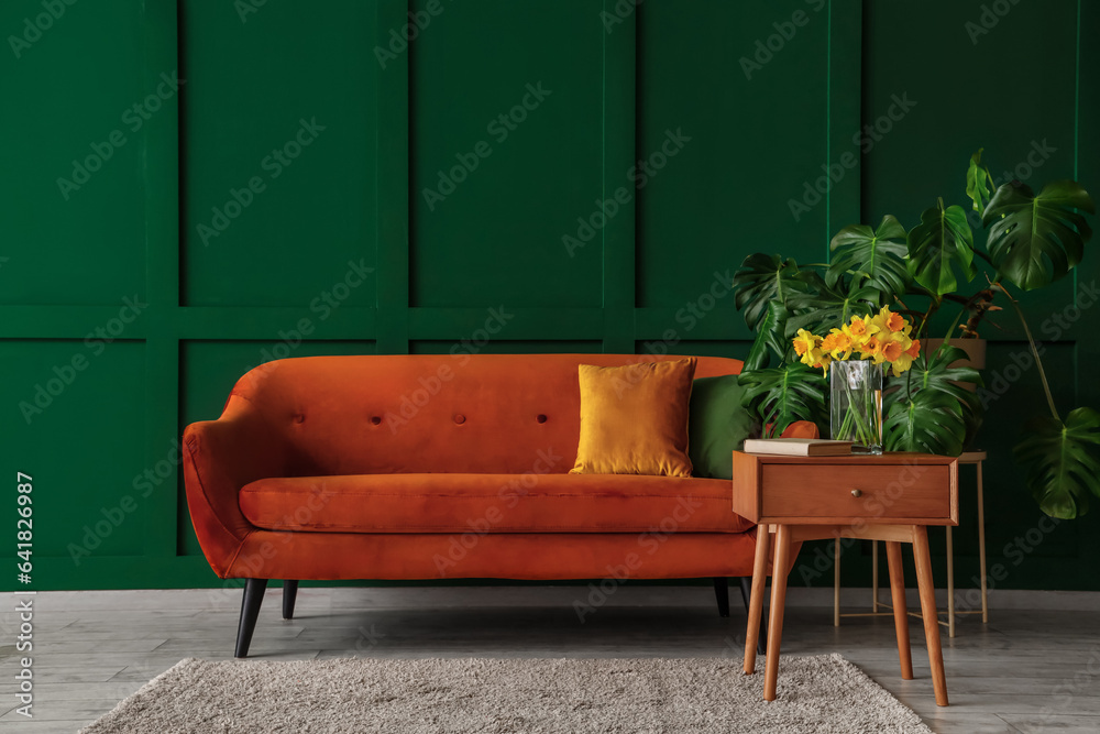 Interior of living room with brown sofa and narcissus flowers on end table