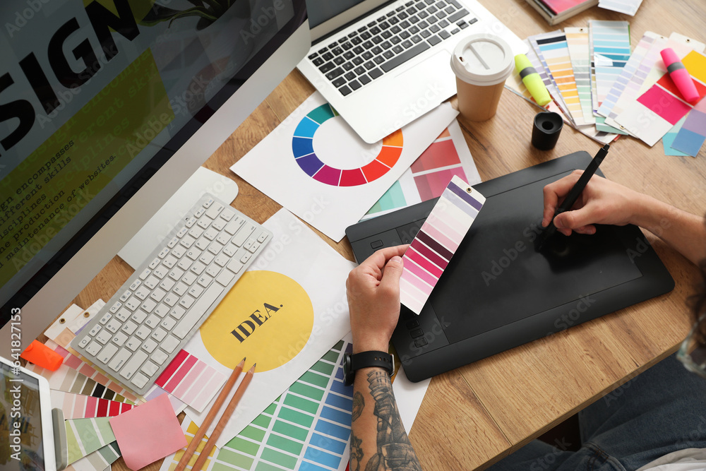 Male graphic designer working with tablet and color palette in office, closeup